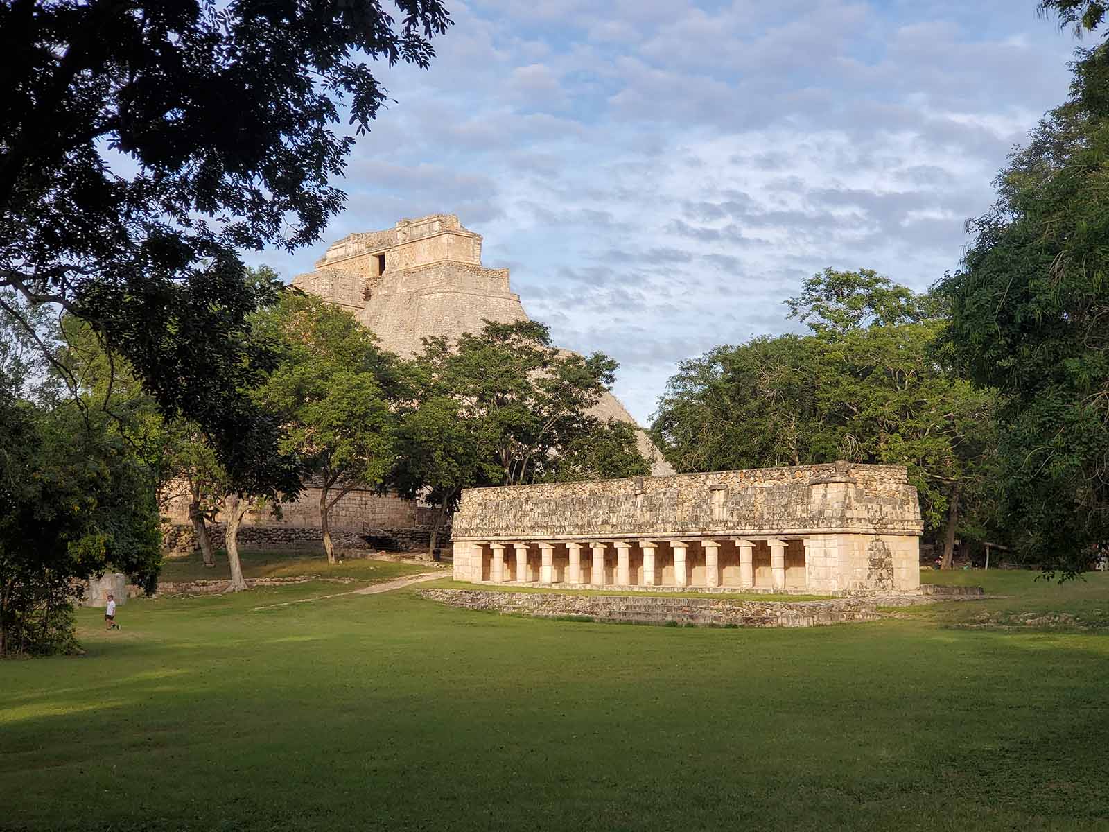 The later afternoon sun at uxmal highlights the peak of the pyramid of the magician and the columns of the house of the iguana